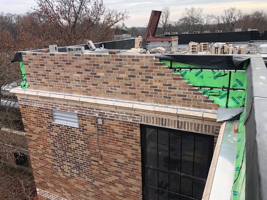 Flashing being installed on a brick parapet.