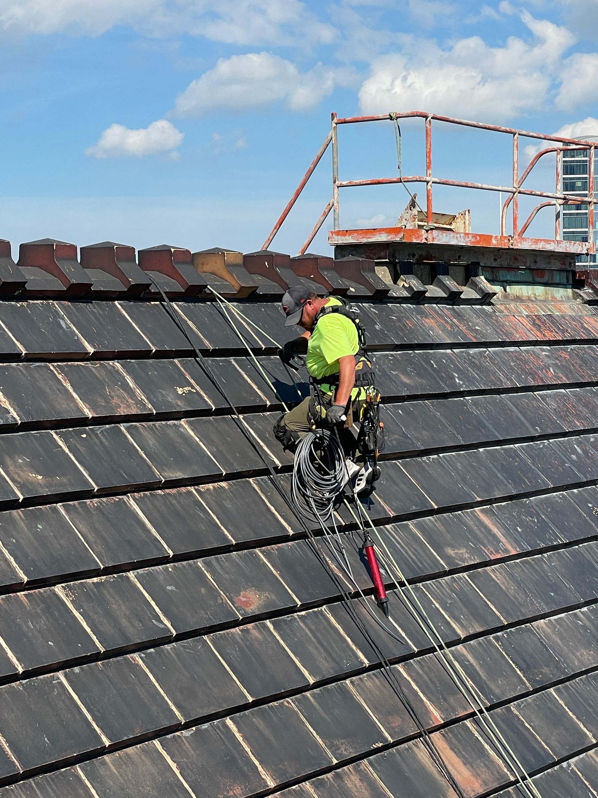 A man is climbing a roof with a rope attached to him on Chicago Civic Opera
