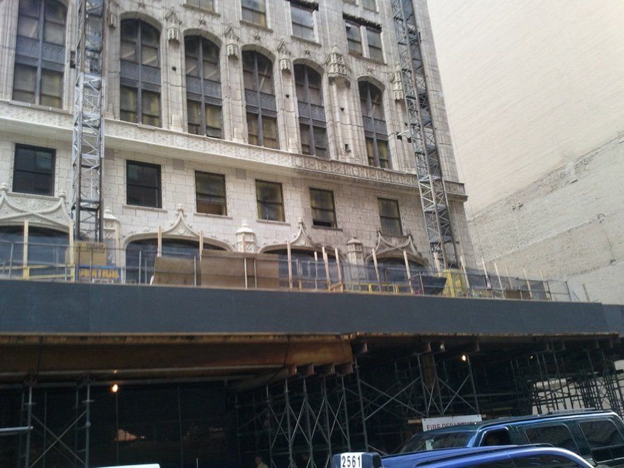 Building facade under construction, scaffolding, blue vehicle.