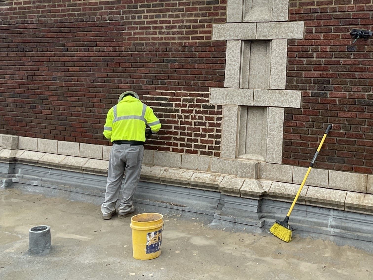RestoreWorks crew member cleaning a brick masonry wall at Evanston High School in the Chicago suburbs, using gentle restoration techniques to remove surface buildup and stains