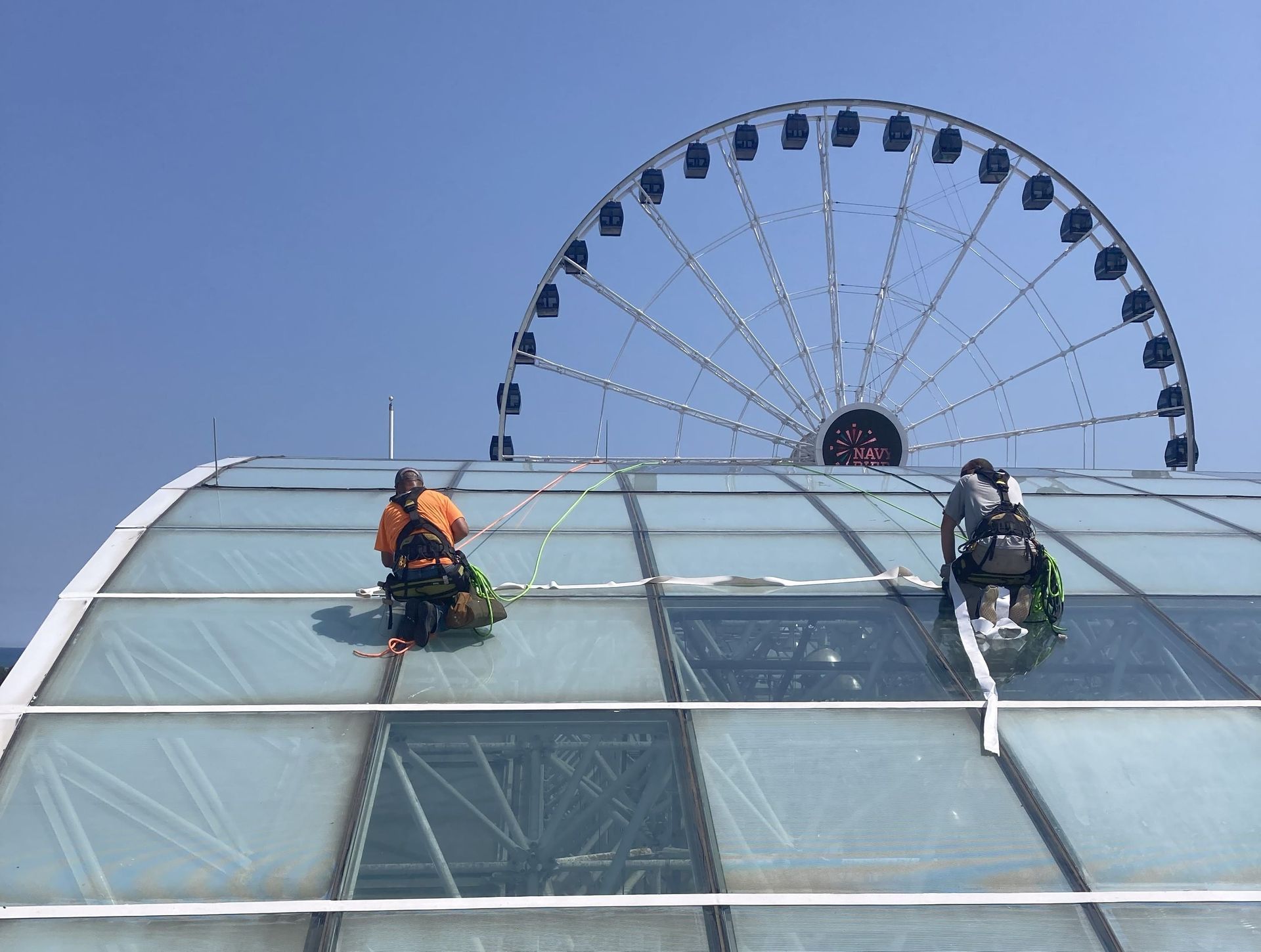 RestoreWorks technicians using rope access to seal the Crystal Garden glass dome at Navy Pier, completing restoration work while suspended above the structure.