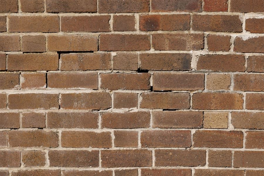Red brick wall with horizontal mortar lines and a few chipped, darker bricks