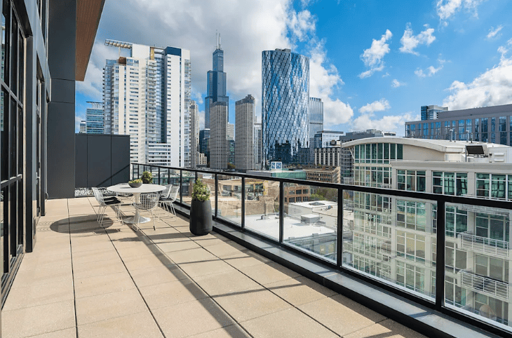 Rooftop terrace overlooking a city skyline with glass skyscrapers under a blue sky