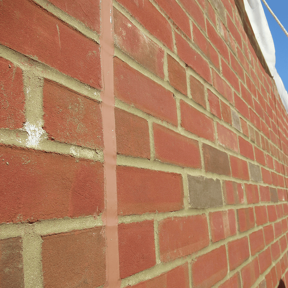 Close-up of a red brick wall with light mortar and a vertical seam.