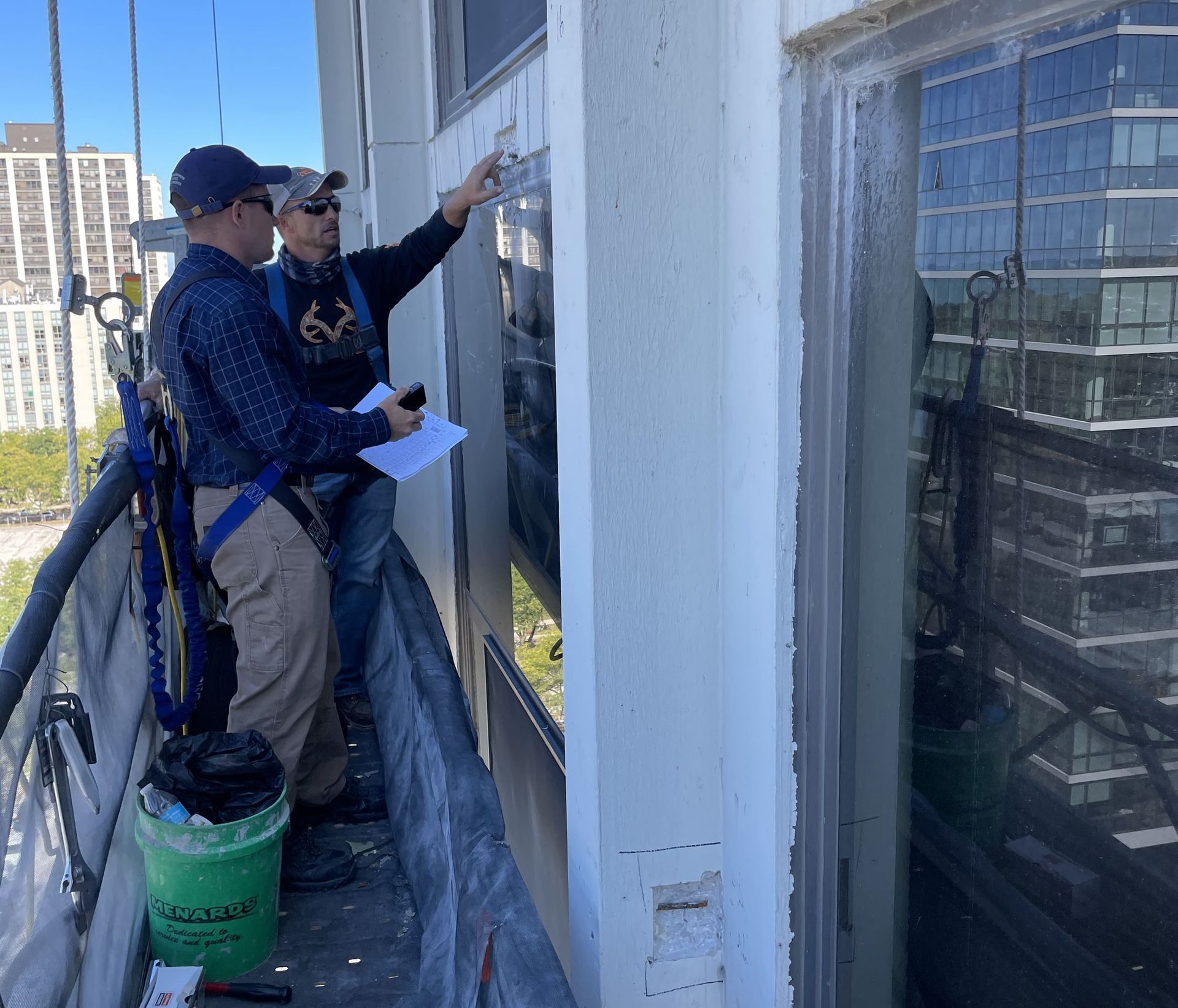 Two workers on a window-washing platform cleaning the exterior of a building.
