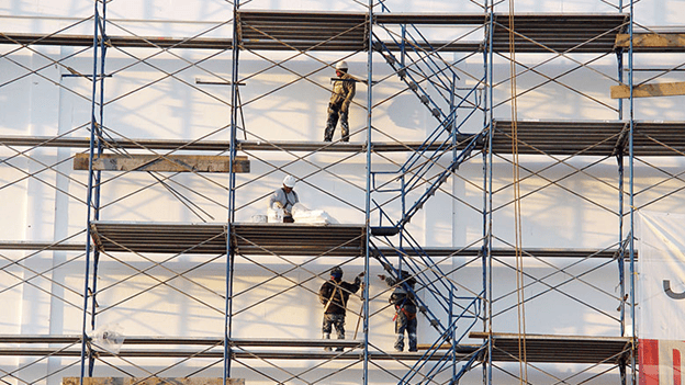 Workers on metal scaffolding outside a building under construction.