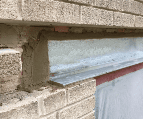 Glass block window in a beige brick wall with a red trim below