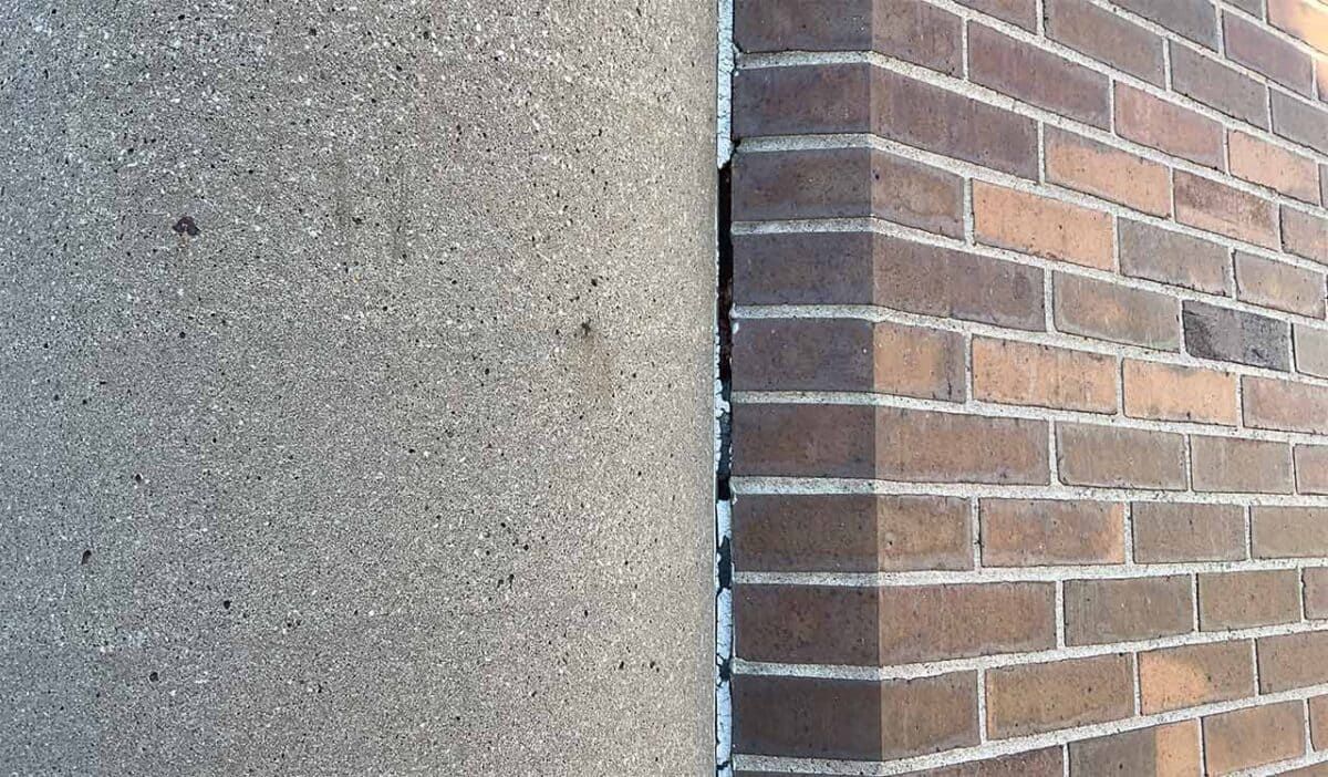 Textured gray wall beside a red brick corner with white trim
