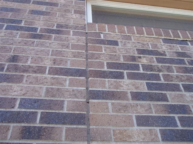 Brick wall with a vertical crack and a small window ledge above it
