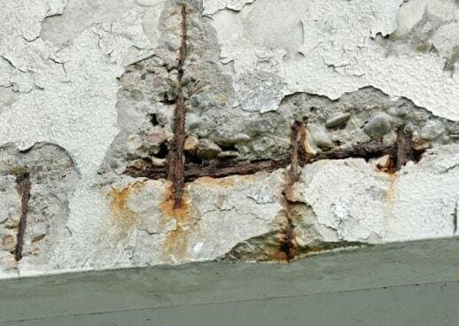 Peeling white wall with rusted cracks and a damaged gray baseboard