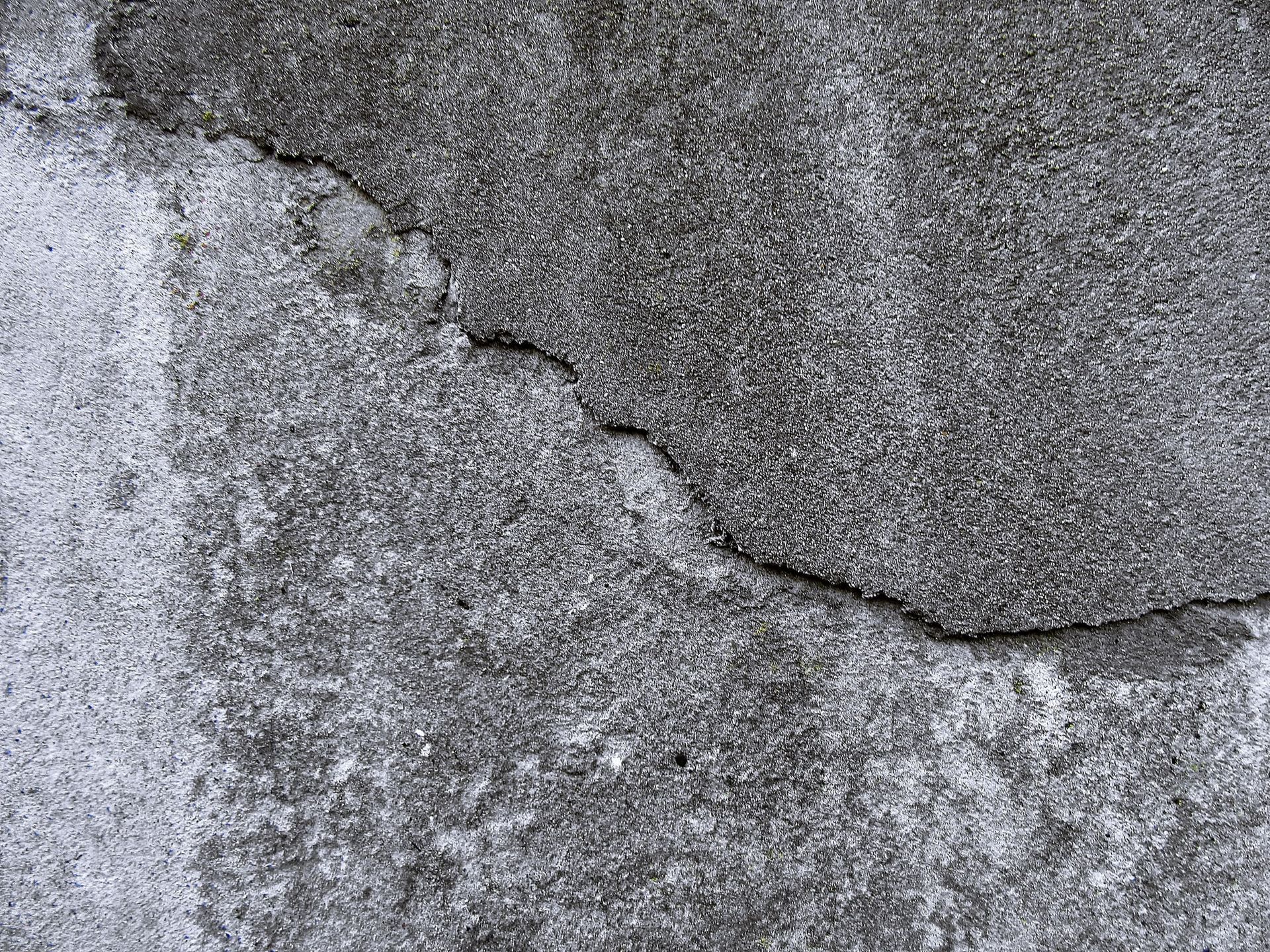Hairline cracking in concrete surface caused by freeze–thaw cycling and moisture intrusion in a building envelope.