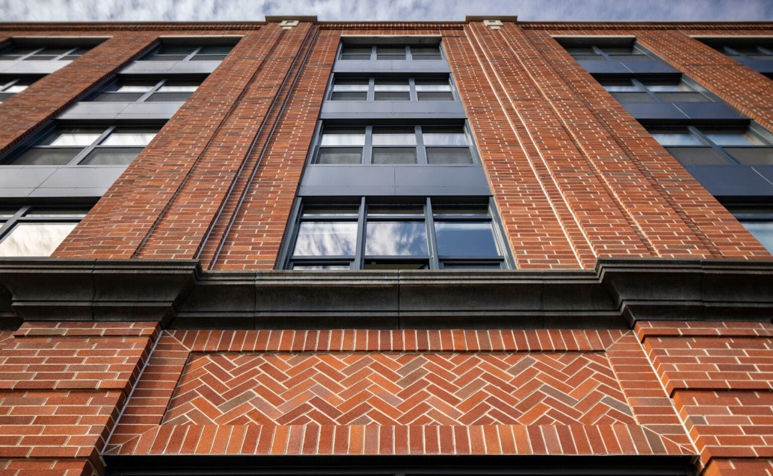 Low-angle view of a red brick building facade with dark-framed windows and black trim
