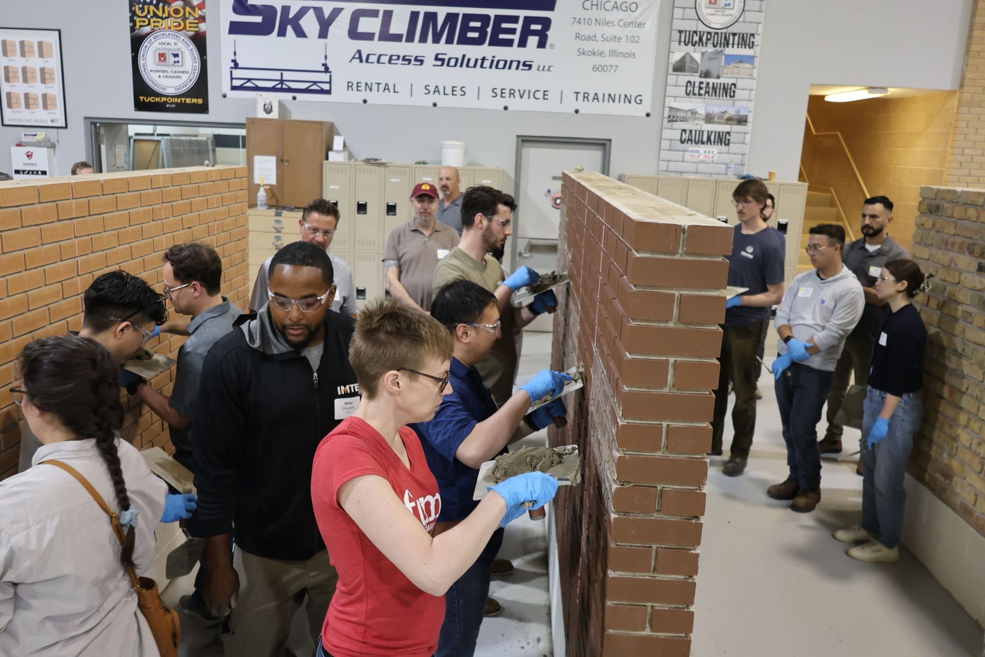 People testing tuckpointing on a brick wall at the International Masonry Institute's facility.