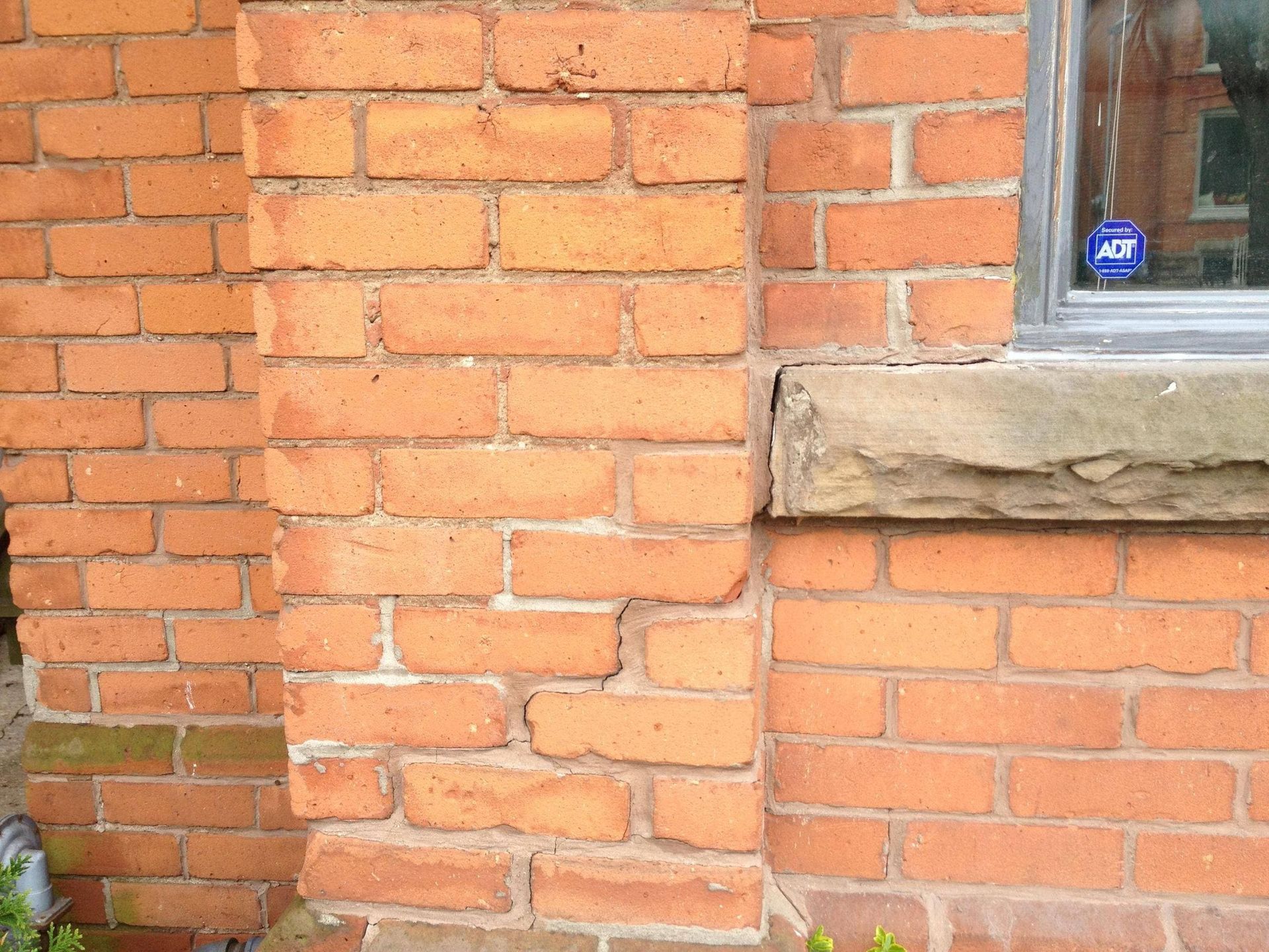 Close-up of a red brick wall with a small window and stone sill