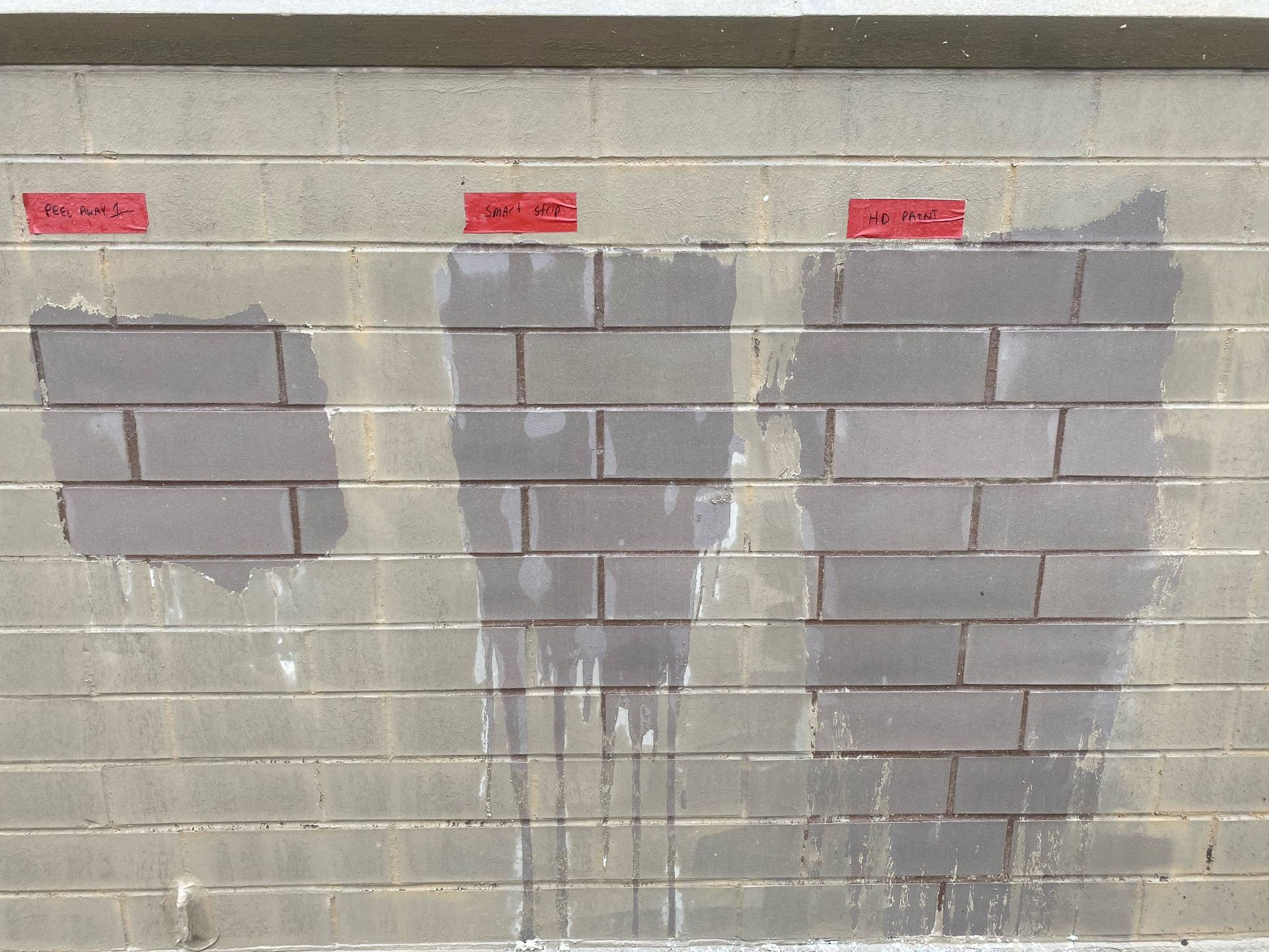 Gray cinder block wall with several patched areas marked by red labels above each section