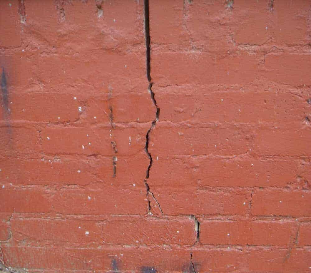 Cracked red brick wall with a vertical split running down the center