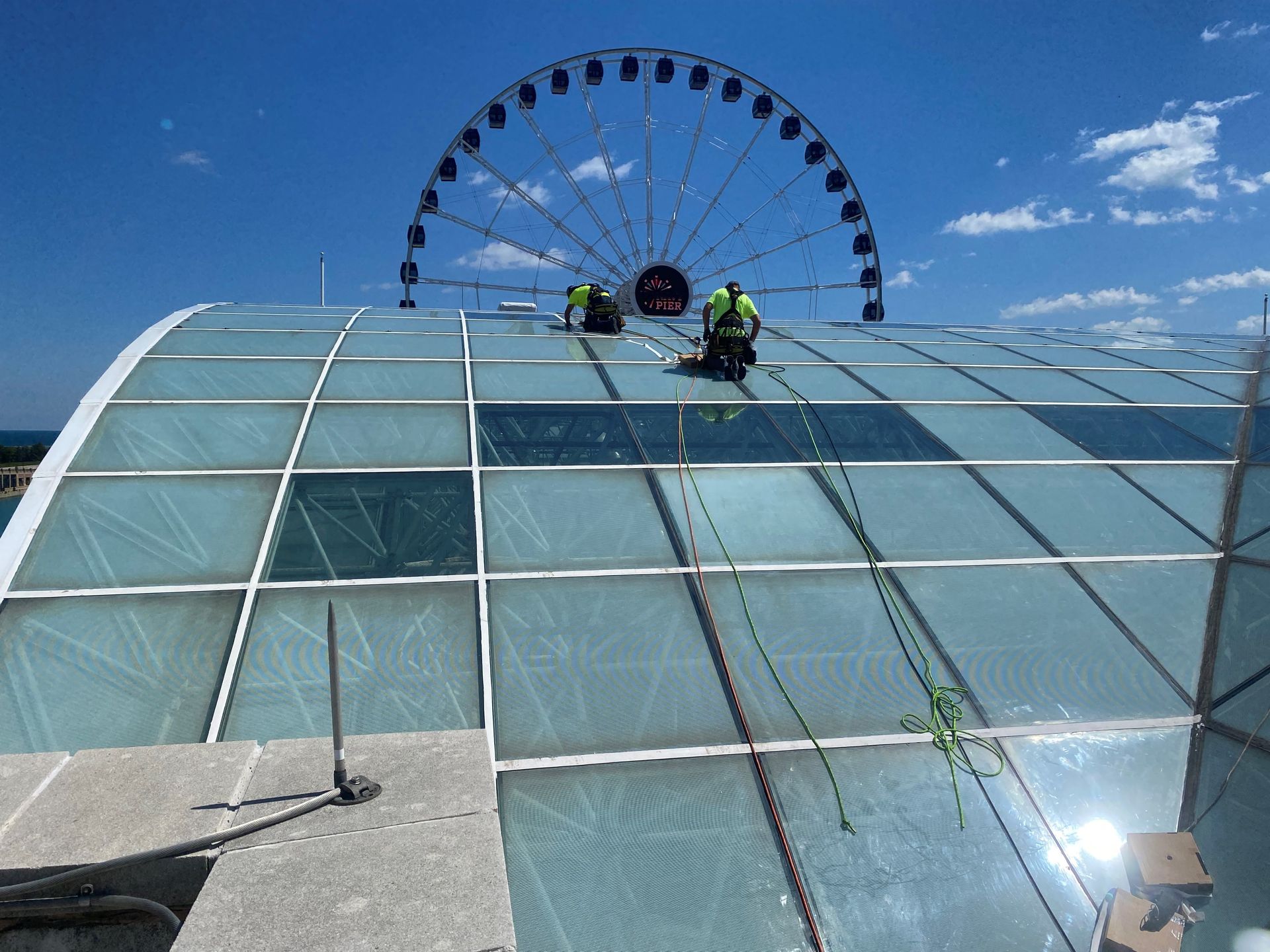 Two RestoreWorks Masonry Restoration employees replacing glass sealant on Navy Pier's Glass Garden