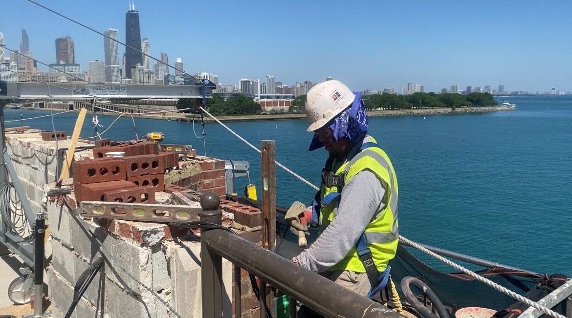 A RestoreWorks Masonry Restoration employee working on top of Navy Pier with a view of the Chicago in the background