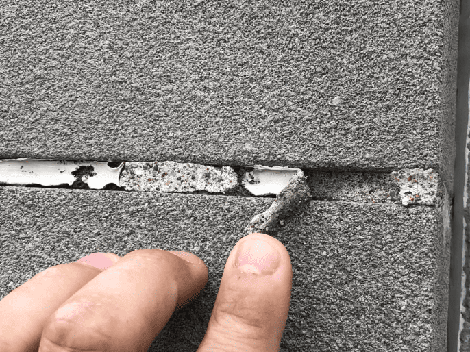 Close-up of deteriorated exterior sealant pulling away from a masonry joint, illustrating early warning signs of sealant failure.