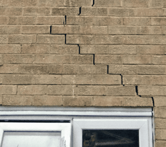 Cracked tan brick wall above a white-framed window
