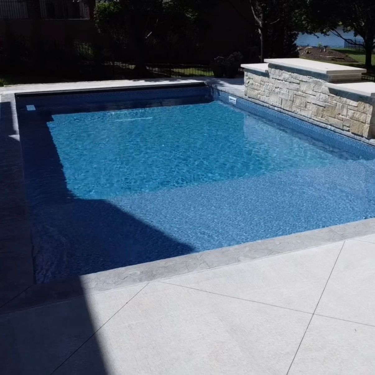 Vinyl liner pool with tanning ledge, water feature wall, and automatic cover in Leawood Kansas