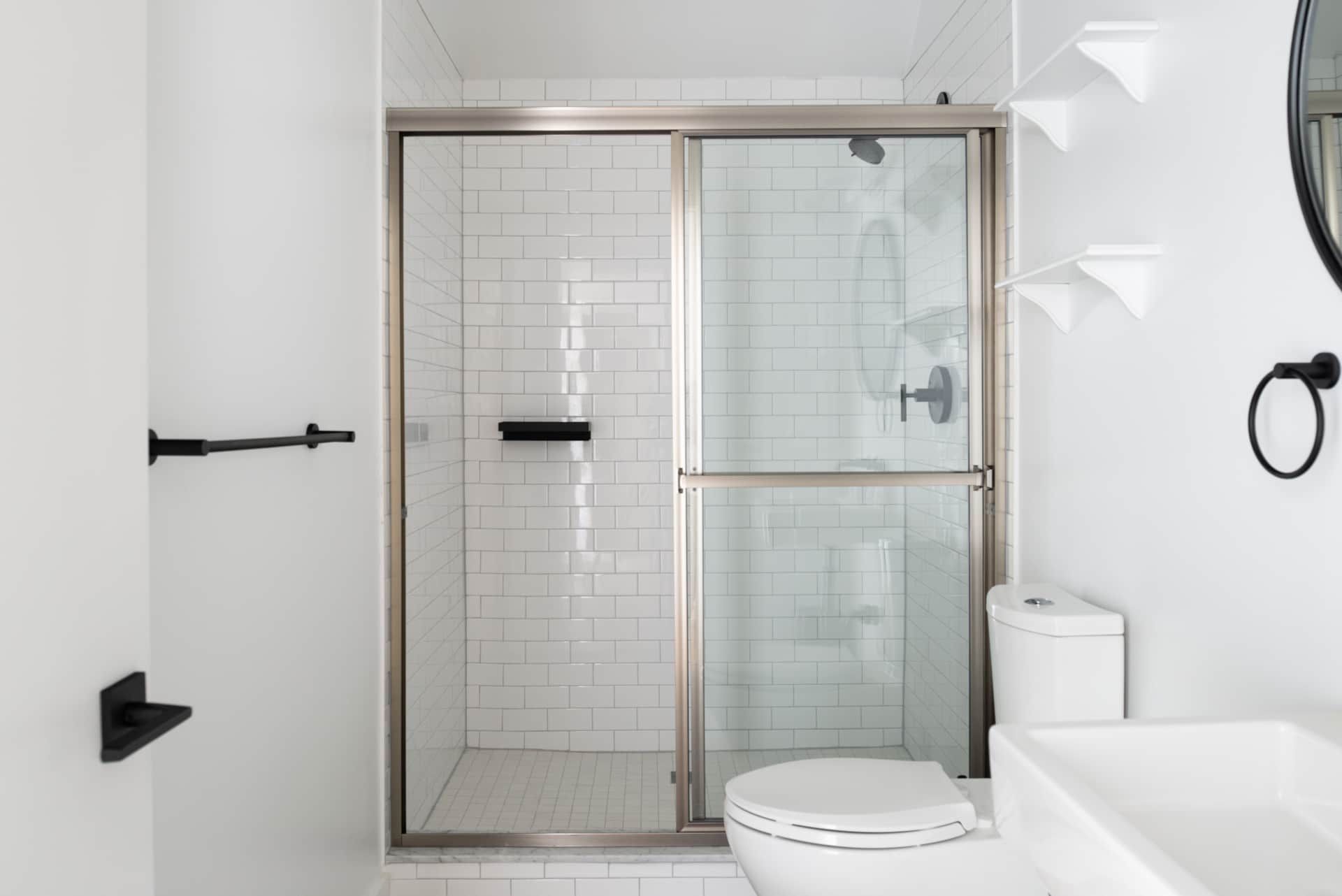 Modern white bathroom with glass shower, toilet, and sink