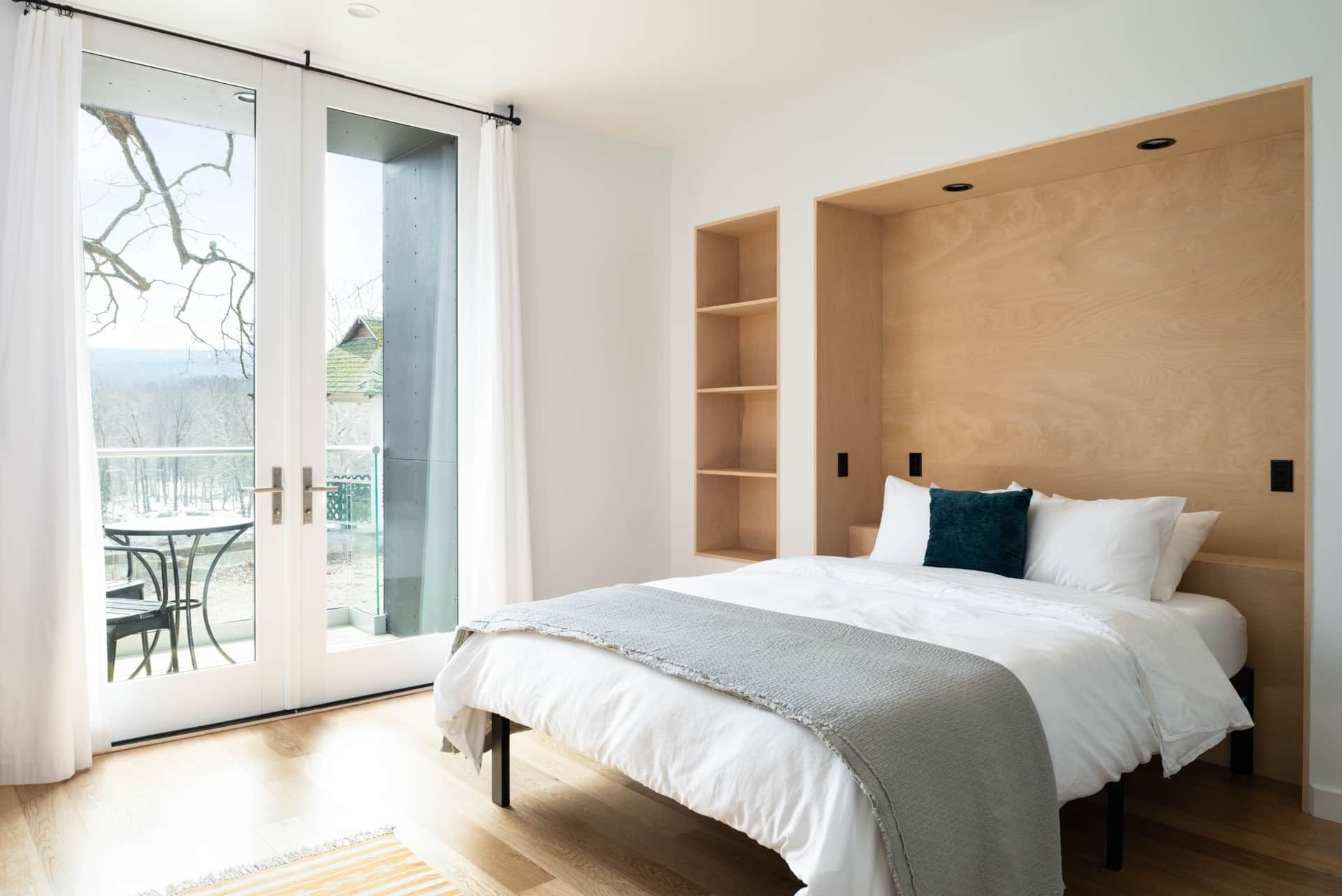 Bright bedroom with a bed, wood accent wall, and sliding doors to a balcony