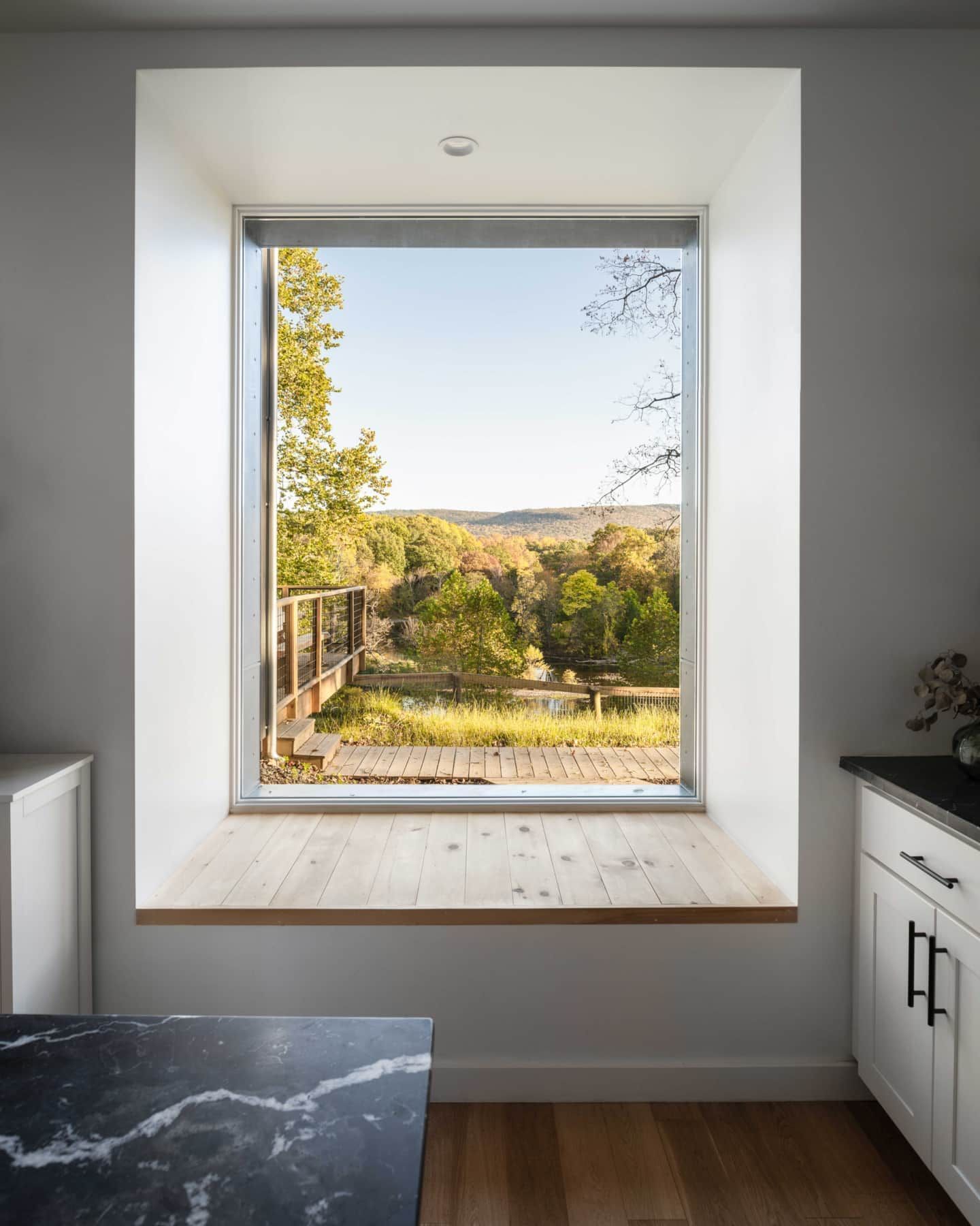 Bright kitchen window seat overlooking a sunny backyard and distant trees