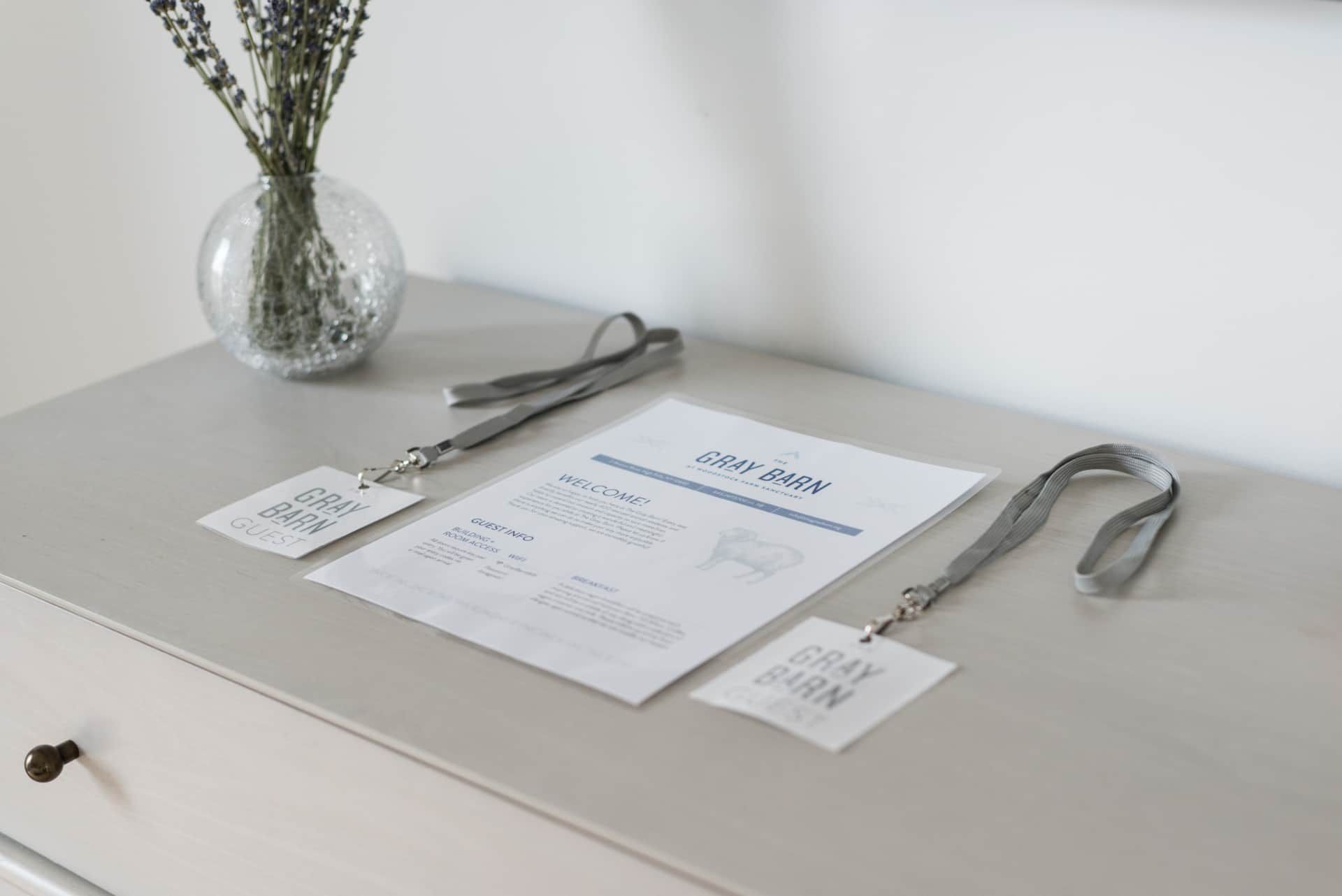 Minimal table setting with two menus, silverware, and a vase of flowers on a light dresser
