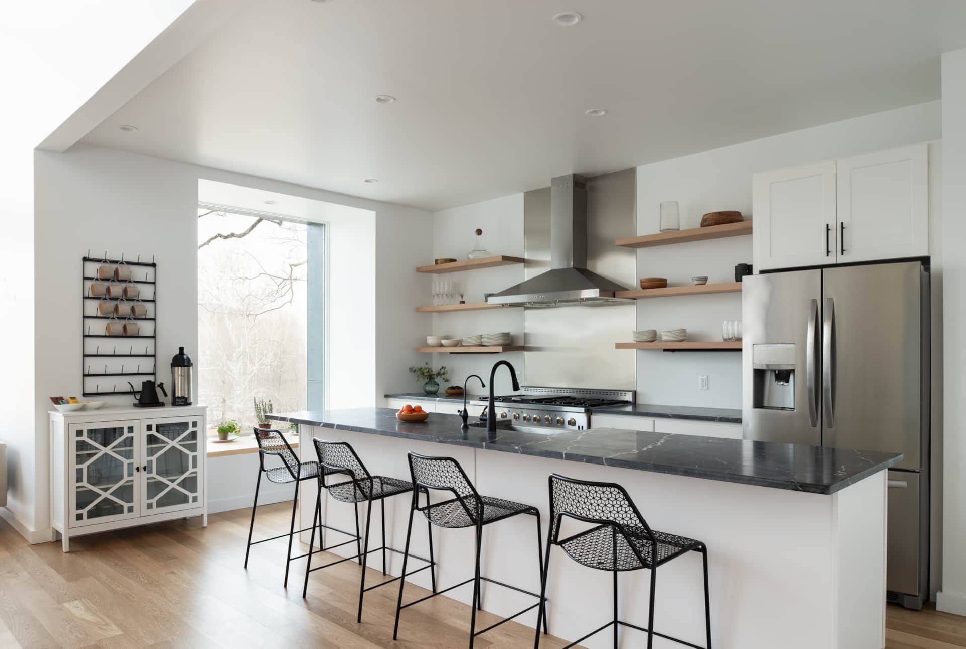 Bright modern kitchen with white cabinets, stainless steel fridge, island, and bar stools