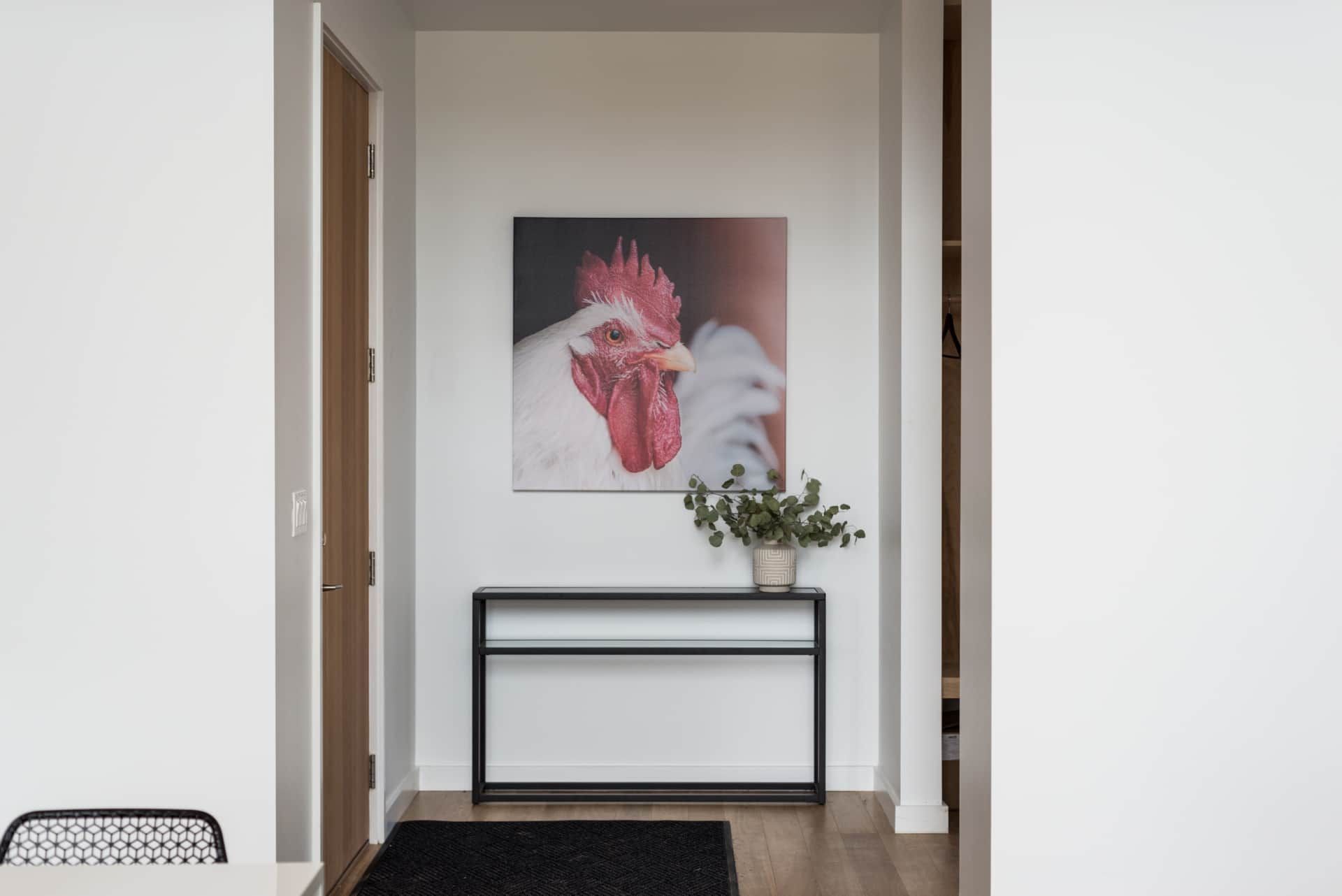 Minimal entryway with console table, flowers, and floral wall art above a black rug.