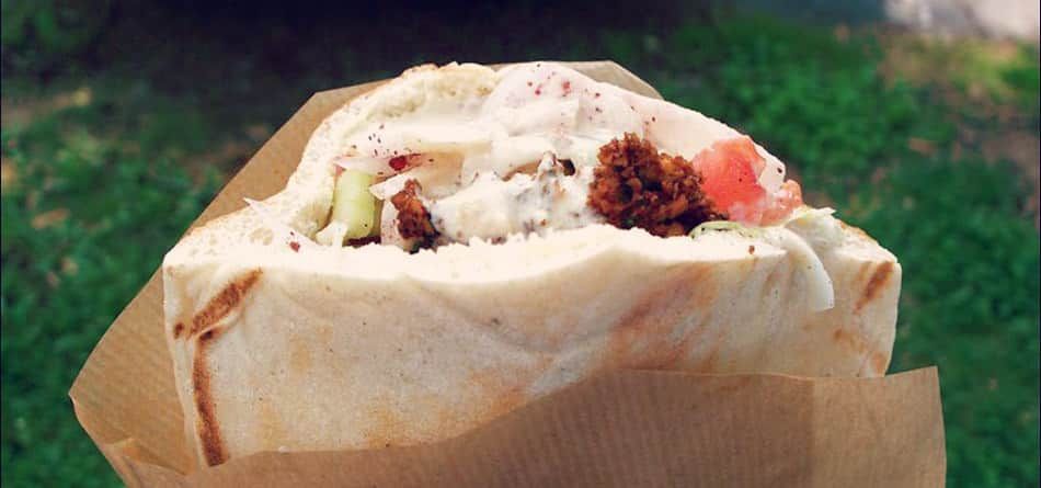 Partially eaten wrap with visible filling held outdoors against a grassy background