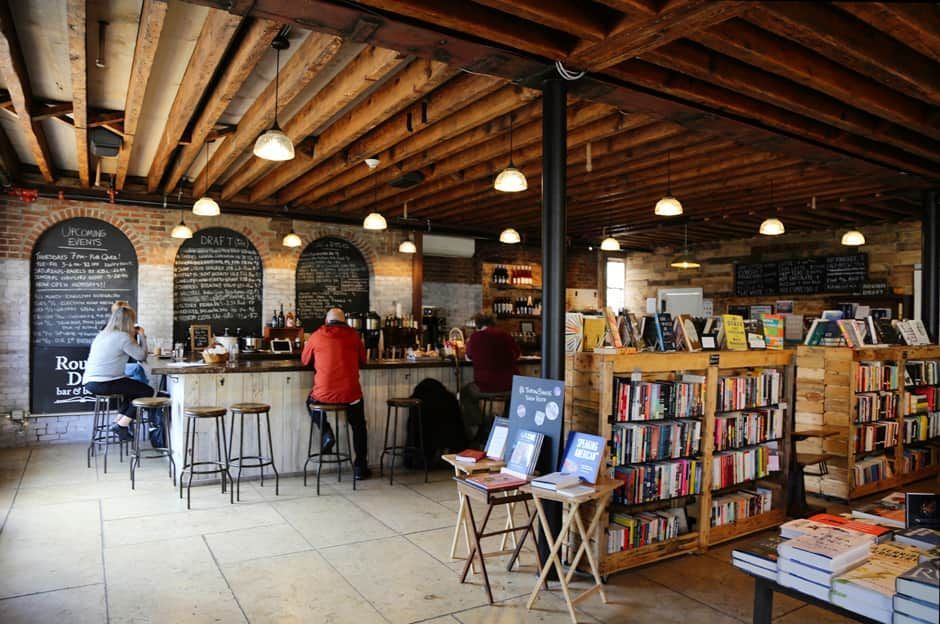 Cozy bookstore café with exposed beams, a long counter, and shelves of books in a warm brick interior
