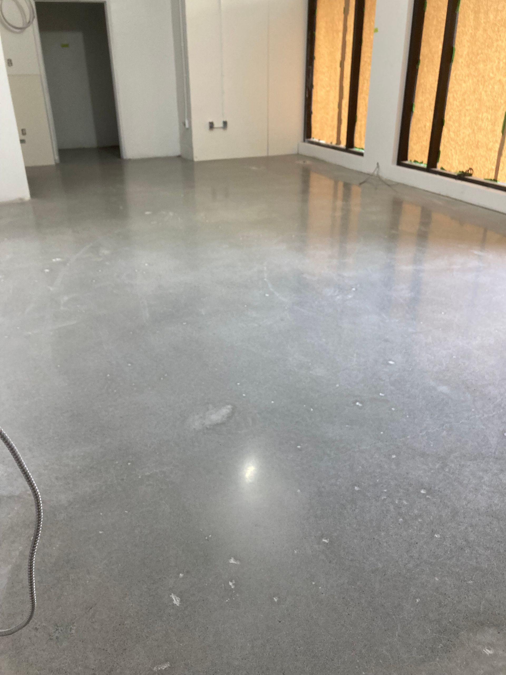 Une grande pièce vide avec un sol en béton et des fenêtres.