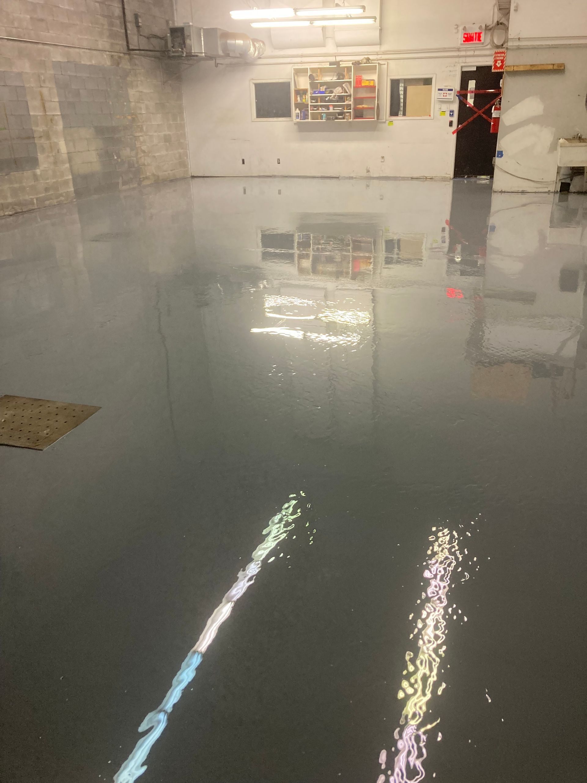 A room with a gray floor and a red exit sign