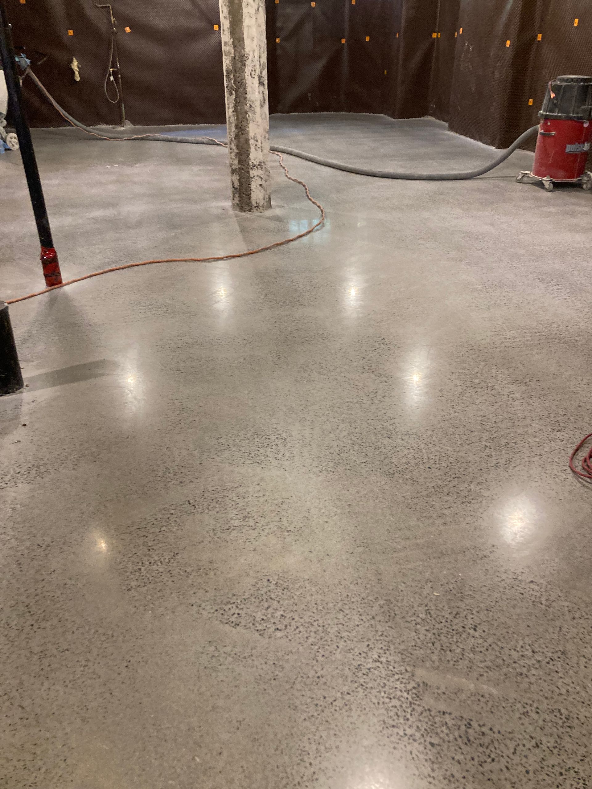 Une personne nettoie un sol en béton avec un aspirateur.
