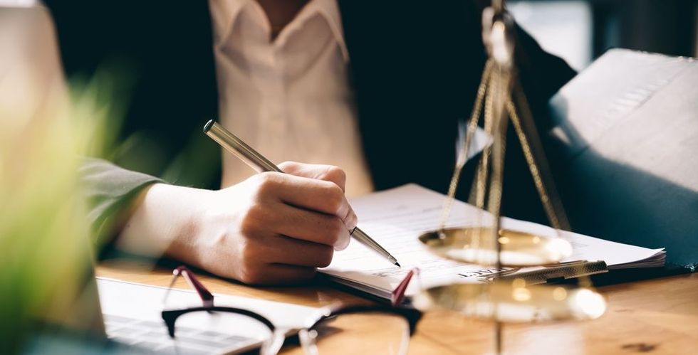 Lawyer taking notes, with a scale of justice on the table.