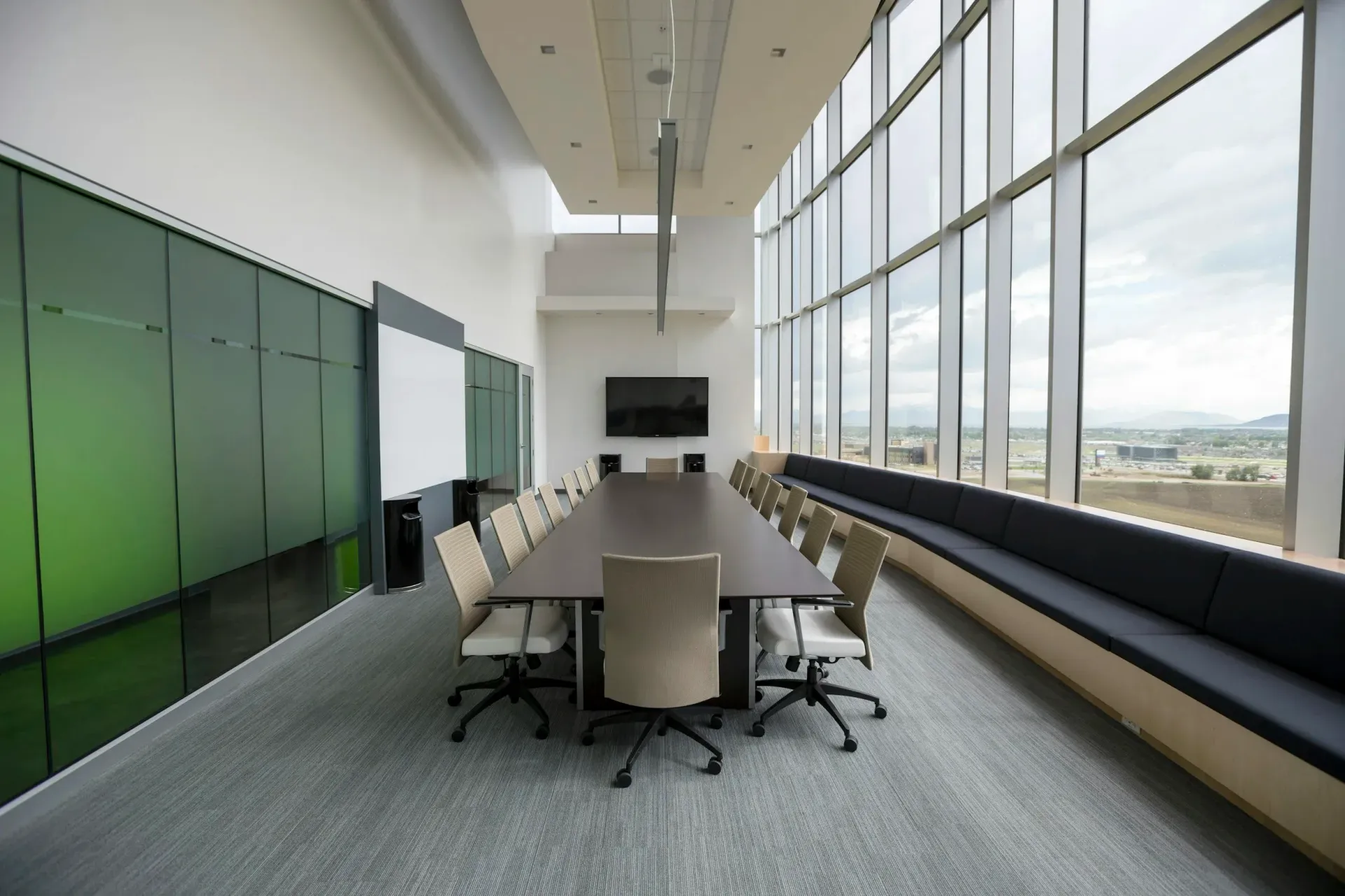 Conference room with long table, chairs, and large windows with bench seating.