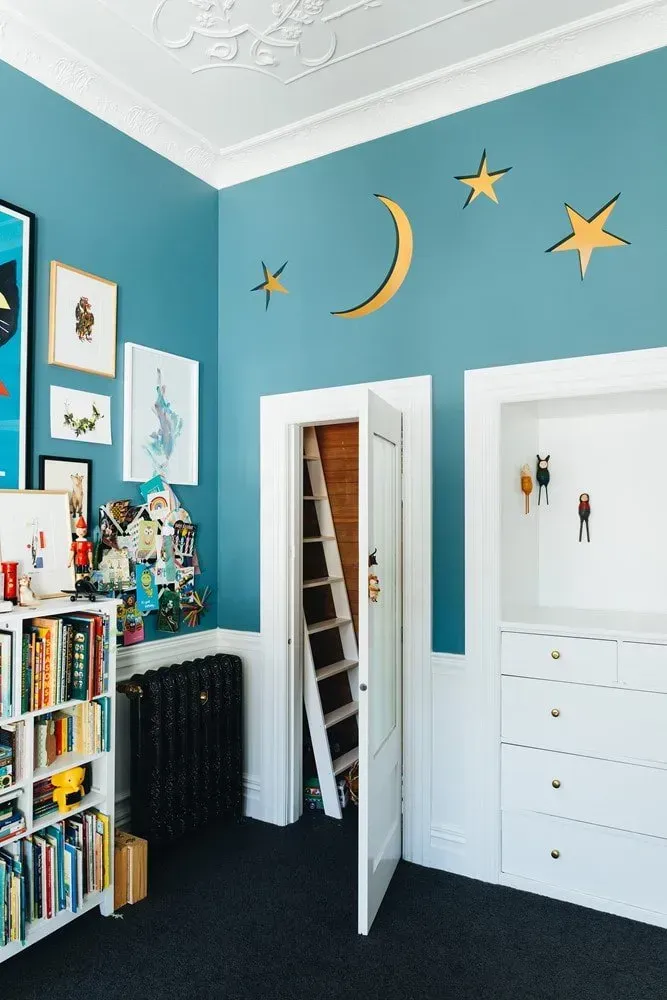 Colorful child’s bedroom with moon and stars wall decals, bookshelves, and an open door to a closet