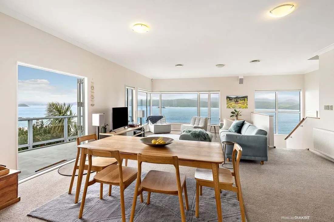 Bright open living-dining room with ocean views, wood table, blue sofa, and large windows