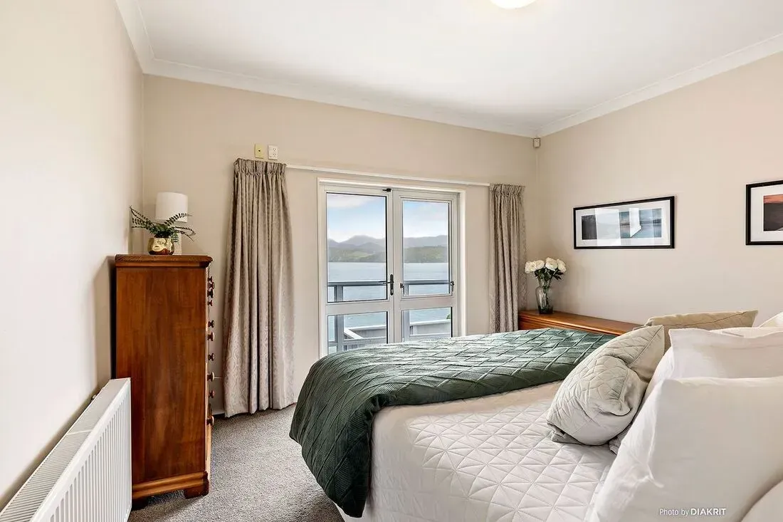 Cozy bedroom with a bed, dresser, window, and beige walls in soft neutral tones