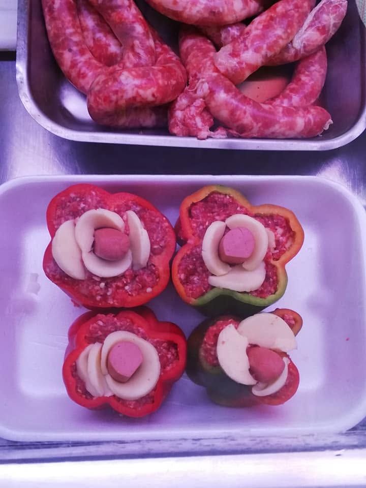 Vassoio di salsicce in alto e peperoni ripieni con cipolle affettate in basso