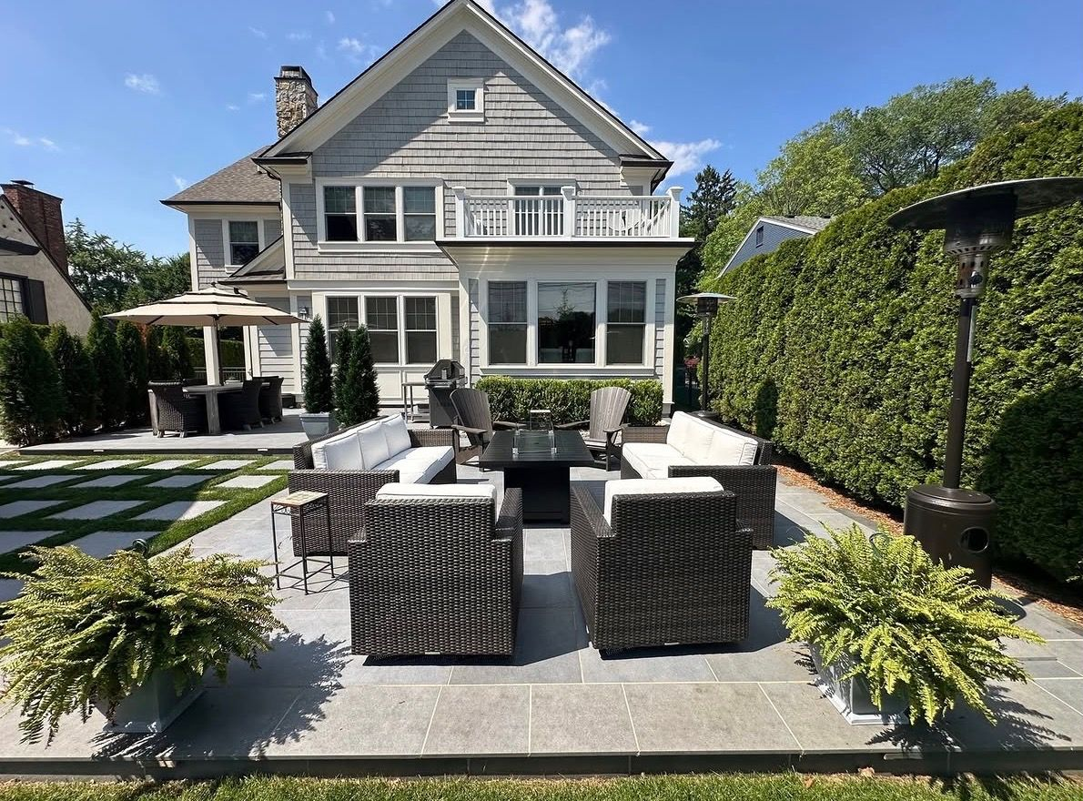 Backyard patio with wicker seating and a gray house with white trim in the background