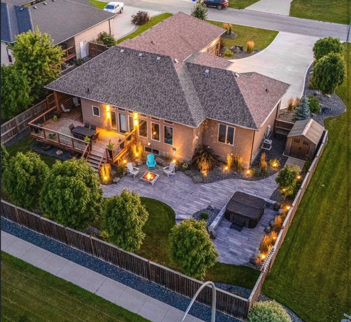 Backyard patio with lit water features, stone landscaping, and outdoor seating at dusk