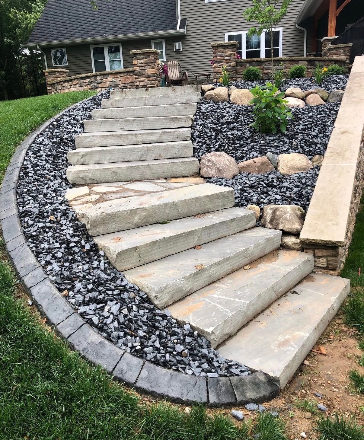Curved stone steps bordered by black gravel in a landscaped front yard.