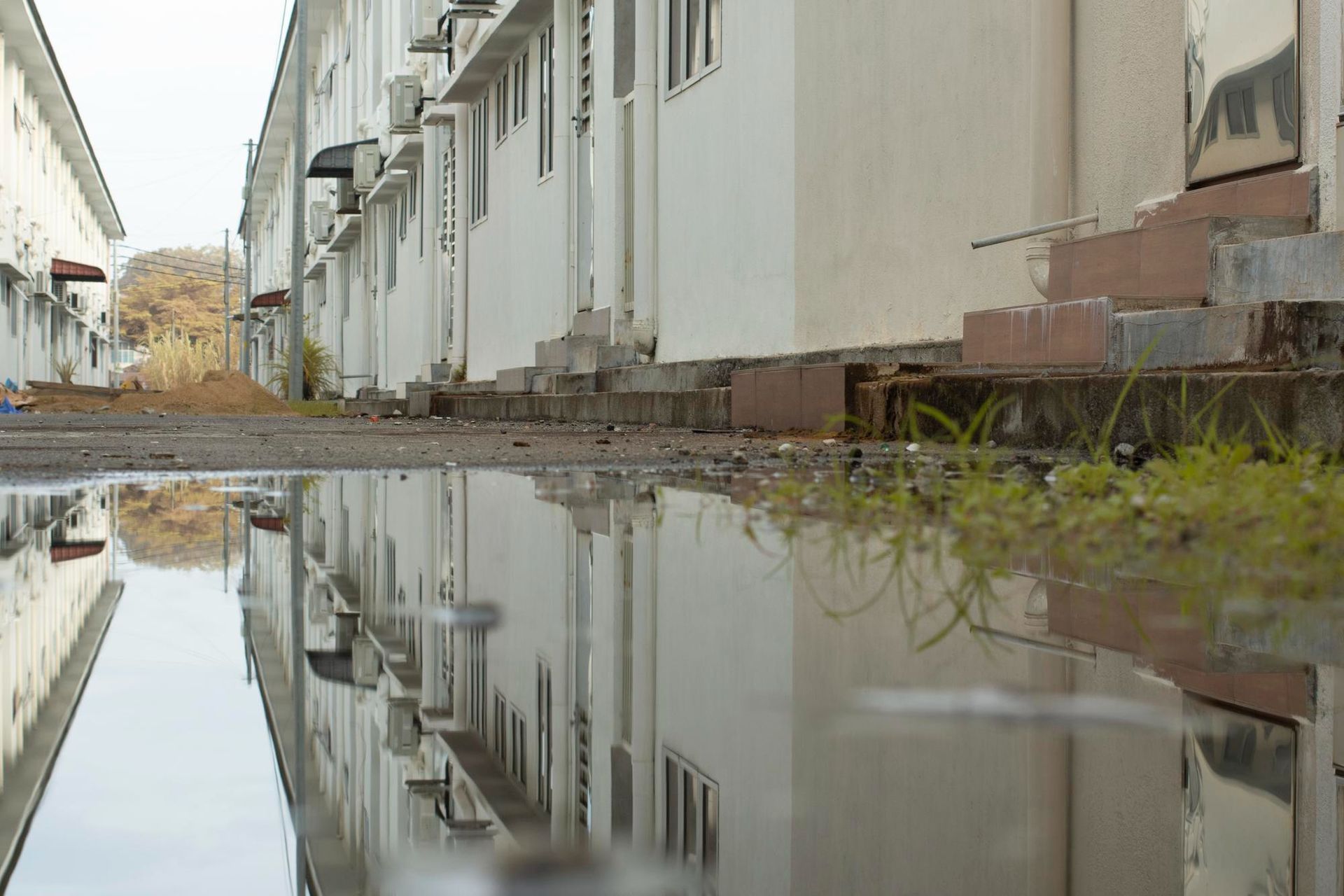 Reflection of buildings in a puddle. White buildings with windows, reflecting on wet ground.