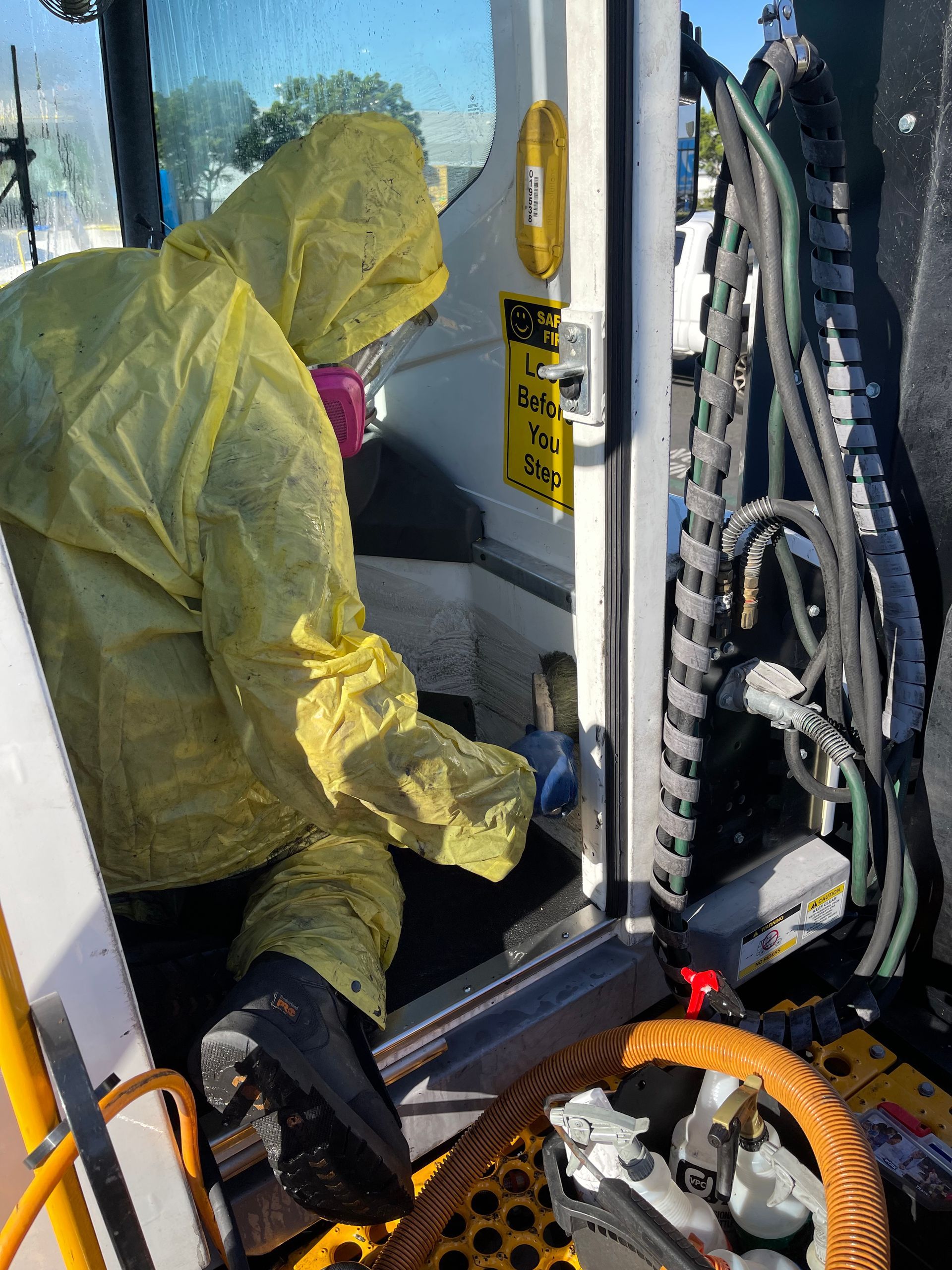 A man in a yellow protective suit is working on a machine.