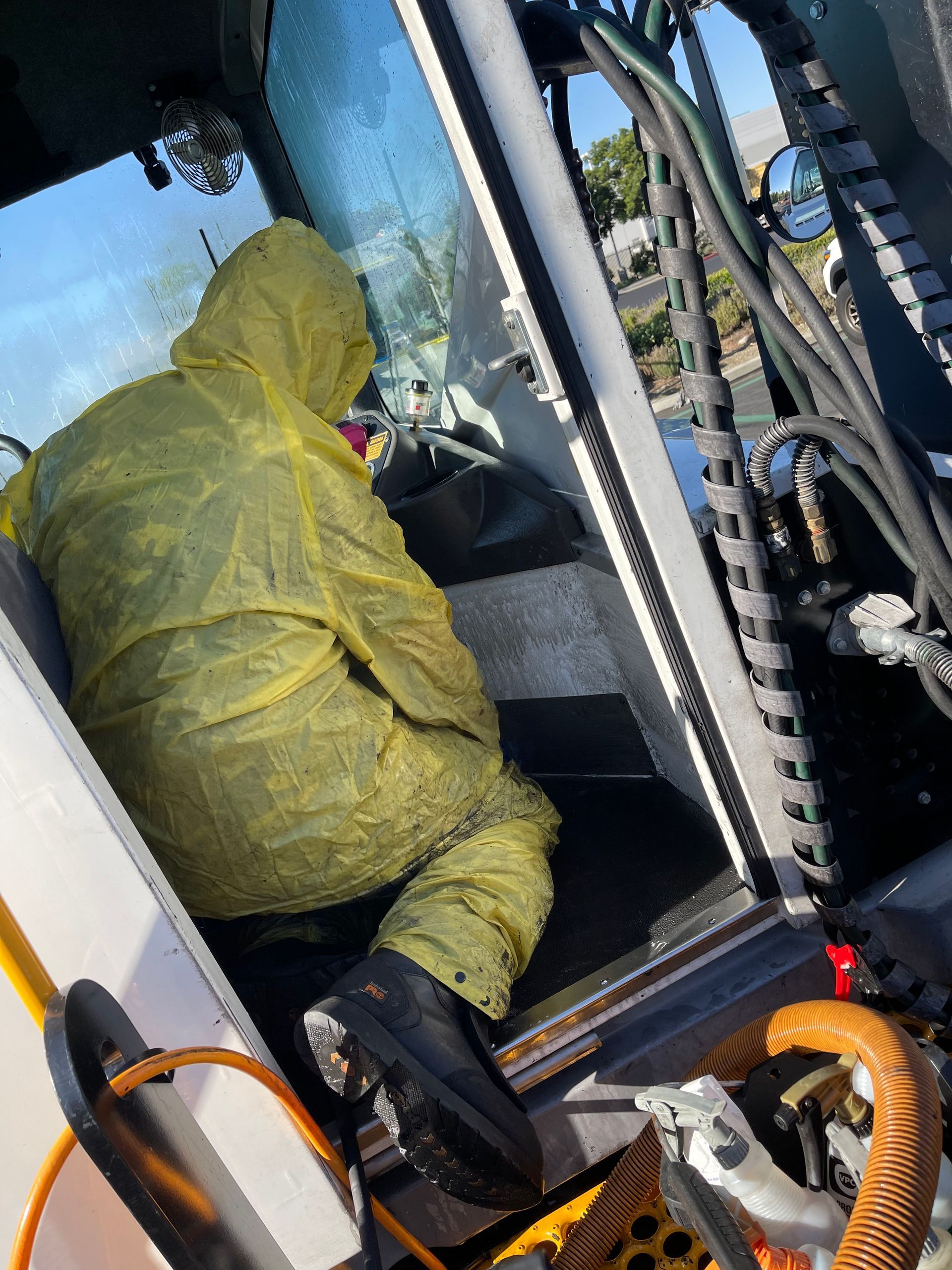 A man in a yellow protective suit is sitting in the driver 's seat of a tractor.