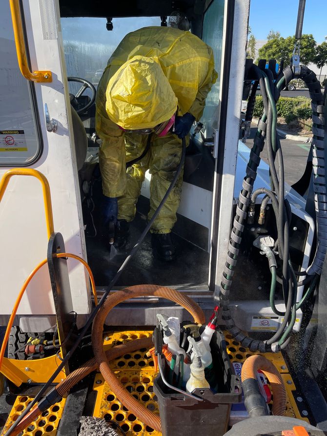 A man in a yellow protective suit is working on a vehicle.