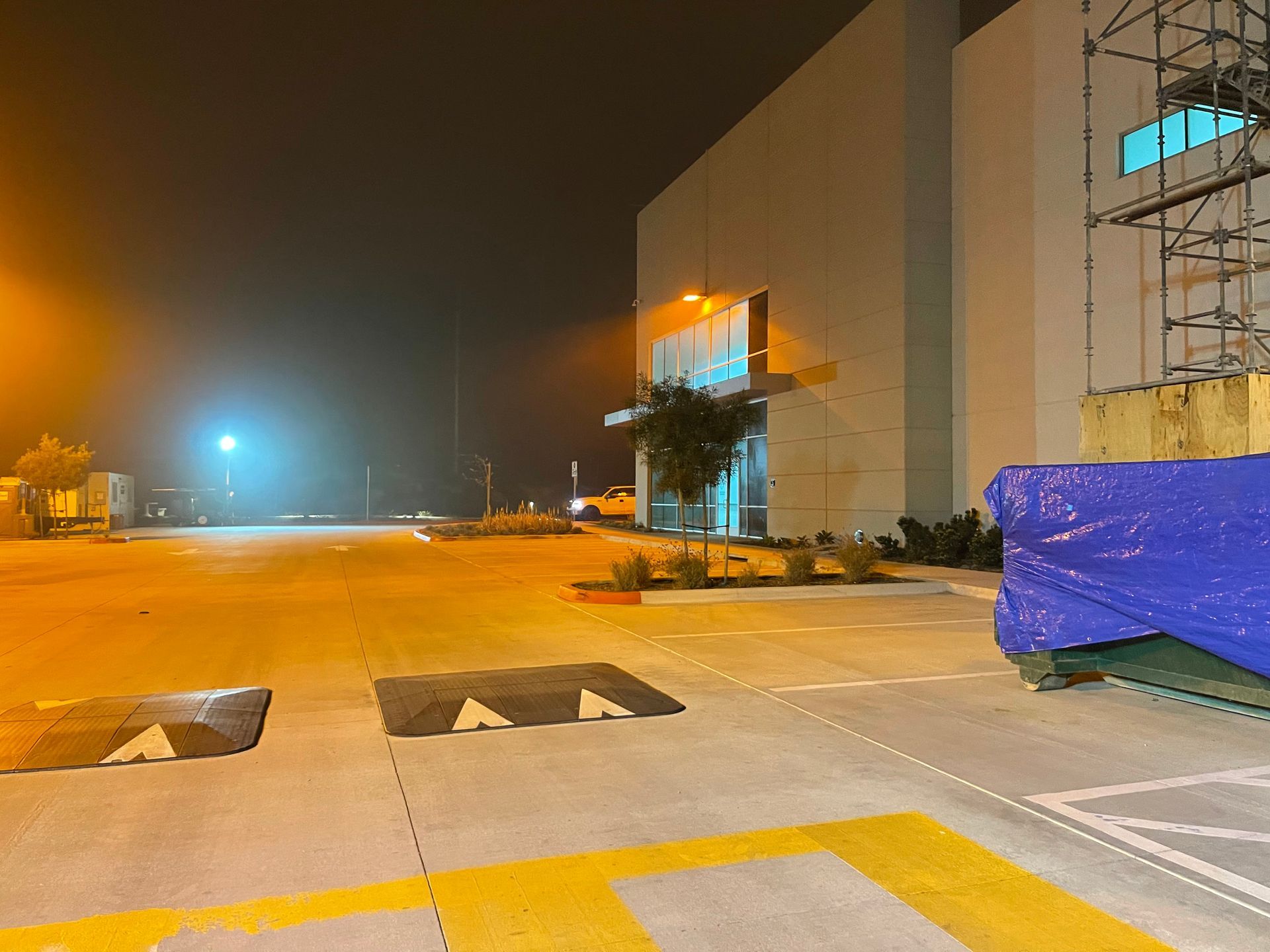 A parking lot with a blue tarp on the side of it at night.